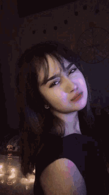 a woman in a black dress looks at the camera