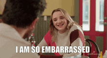 a woman in a sweater is sitting at a table with a man and says `` i am so embarrassed '' .