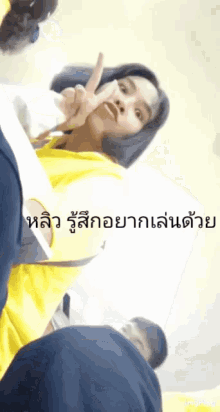 a woman in a yellow shirt giving a peace sign in a foreign language