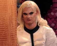 a drag queen with blonde hair and earrings is making a face