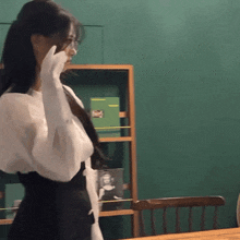 a woman wearing white gloves is standing in front of a book shelf