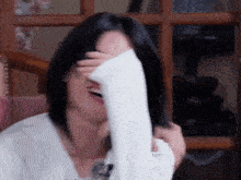 a woman is covering her face with her hand while smiling .