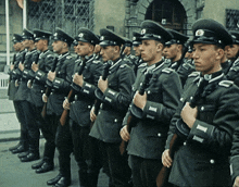 a group of men in military uniforms are standing in a line holding guns