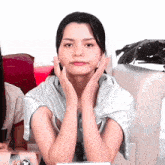 a woman sitting on a couch with her hands on her face looking at the camera