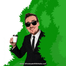 a man in a suit and tie is holding a cup of coffee behind a green bush