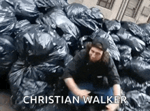 a man is sitting in front of a pile of trash bags .