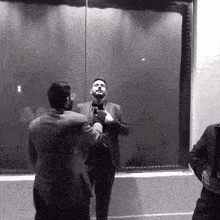 a man in a suit is standing in front of a mirror