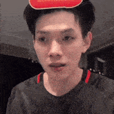 a young man wearing a black shirt and a red and white hat .