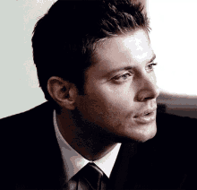 a close up of a man 's face wearing a suit and tie .
