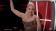 a woman sitting in a chair with her arm in the air and the words #thevoice on the bottom left