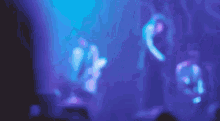 a blurry picture of a woman singing into a microphone on a stage in front of a crowd .