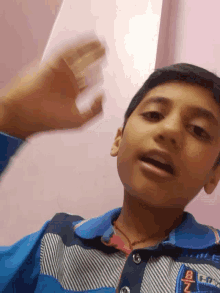 a boy wearing a blue shirt with the letter b on the sleeve