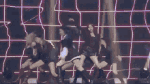 a group of women are dancing on a stage in front of a crowd .