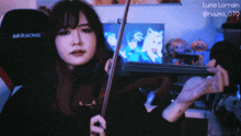 a woman is playing a violin in front of a black akracing chair