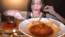 a woman is eating a bowl of spaghetti with a spoon