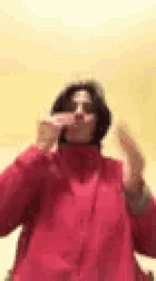 a woman in a red jacket is blowing a kiss with her hands .