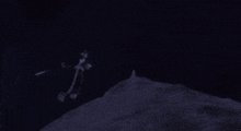 a person in a hat is standing on top of a rock in the dark .