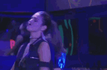 a woman is dancing in a dark room in front of a purple wall .