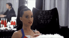 a woman is sitting in a chair with a pillow that says katy perry mvp on it .