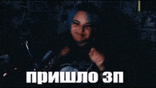 a woman with blue hair is sitting in front of a microphone in a dark room and making a funny face .
