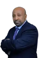 a bald man in a suit and tie with his arms crossed