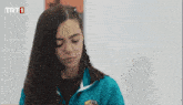a girl in a blue jacket with trt1 on the bottom left