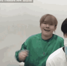 a man in a green sweater is smiling in front of a sign that says treasure a # 4