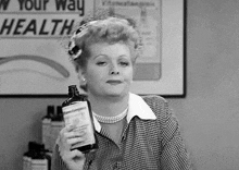 a woman is holding a bottle of liquid in her hand .