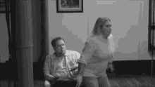 a black and white photo of a man and a woman standing next to each other in a room .