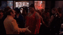 a group of people are dancing in front of a tattoo shop sign