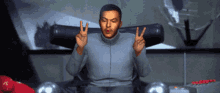 a man in a grey sweater is giving the peace sign