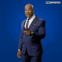 a man in a suit is taking a picture with a fox deportes logo in the background