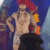 a man without a shirt is dancing on a stage while a crowd watches .