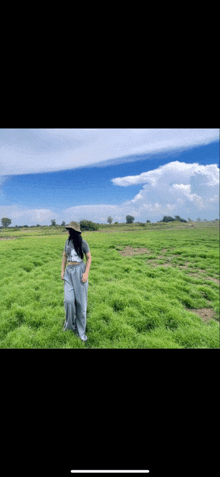 a woman wearing a hat is standing in a field of grass