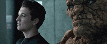 a man in a black shirt is standing next to a statue