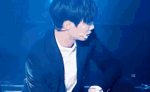 a man in a suit and white shirt is dancing on a blue stage .