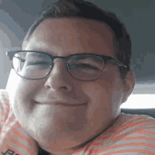 a man wearing glasses and a striped shirt is smiling for the camera