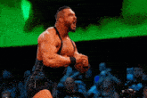 a wrestler is standing in front of a crowd with his arms in the air