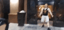 a man in a black tank top and white shorts is dancing on the street