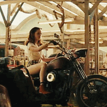 a woman is sitting on a motorcycle in a parking lot