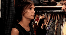 a woman is standing in a closet looking at a man 's face .