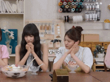 two girls are sitting at a table with a bowl of ice cream and a box that says ' a ' on it