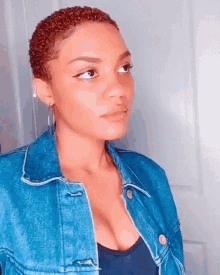 the woman is wearing a denim jacket and earrings .