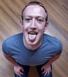 a man in a blue shirt is sticking his tongue out while kneeling down .