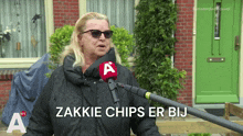 a woman speaking into a microphone with the words zakkie chips er bij on the bottom