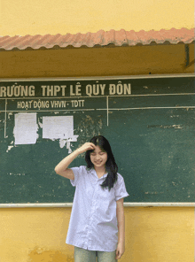 a girl is standing in front of a blackboard that says rương thpt le quy don