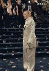 a woman in a white suit is walking down a set of stairs with vogue written on the carpet