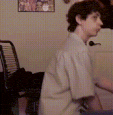a man in a white shirt is standing in front of a chair