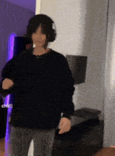 a person wearing headphones and a black shirt is dancing in a room .