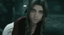 a close up of a man with long hair looking at the camera .